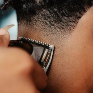 A detailed close-up of hair clippers shaving a person's back of the head, showcasing the art of haircutting.
