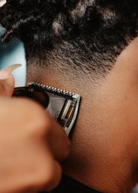 A detailed close-up of hair clippers shaving a person's back of the head, showcasing the art of haircutting.