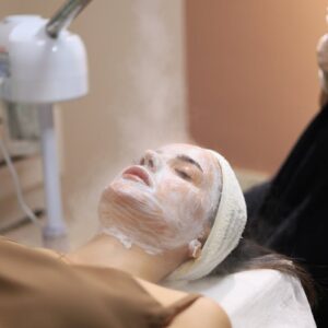 Woman enjoying a facial steam treatment in a serene spa setting.