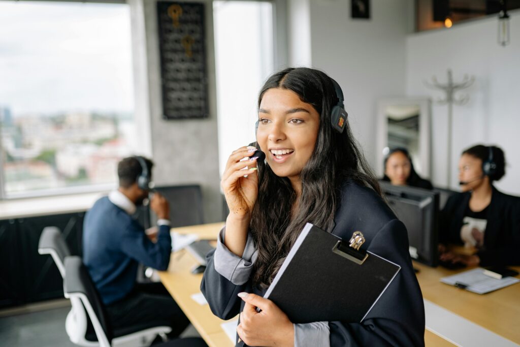 A smiling call center agent with headphones works in a modern office.